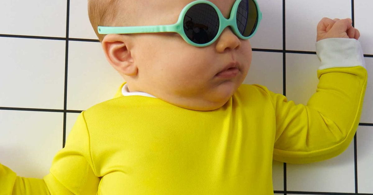 Dziecko leży w żółtym ubranku, na oczach ma okulary