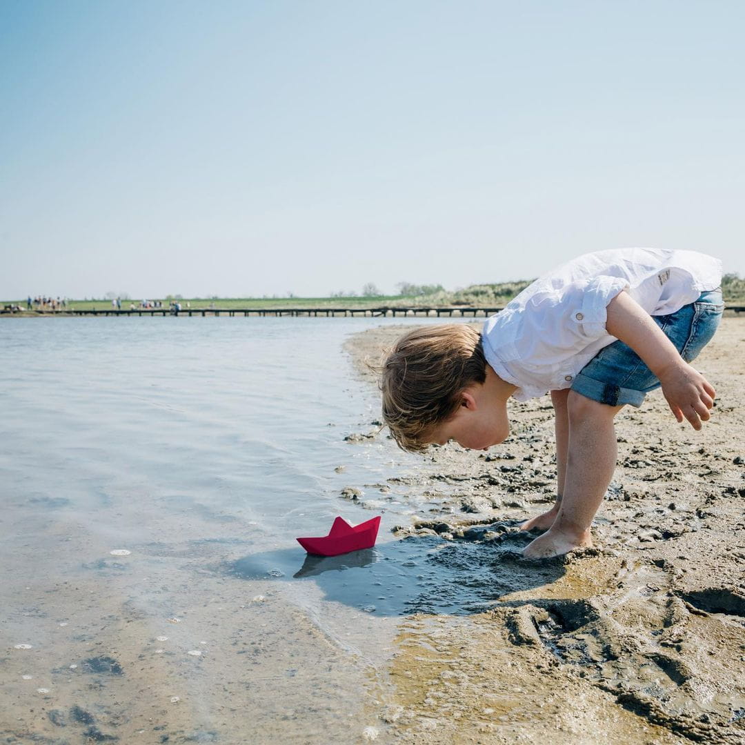 Dziecko nachyla się nad zabawką w wodzie na plaży